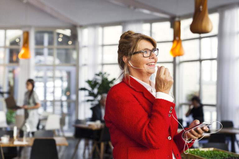 Happy businesswoman talking through earphone while standing in restaurant